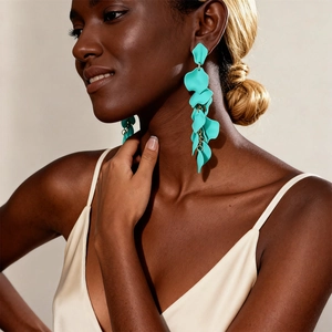 Detail of long turquoise petal drop earrings worn by a model in a beige tank top