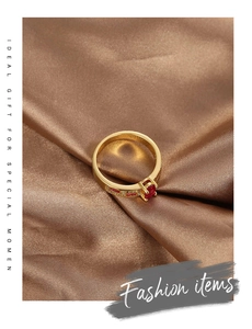 Detailed macro view of 18K gold plated ring with red zircon on brown silk fabric