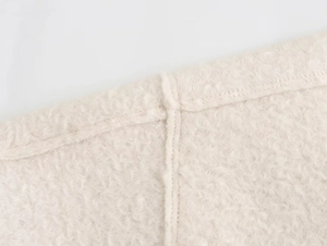 Macro shot of cream sherpa fleece fabric showing detailed texture and stitching