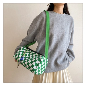Green checkerboard canvas crossbody bag with adjustable strap worn by a model