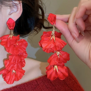 Close-up of red silk fabric flower earrings with layered petals and gold metal studs