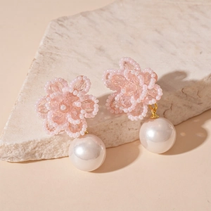 Detail of pink beaded flower earrings with white pearl pendants on stone display