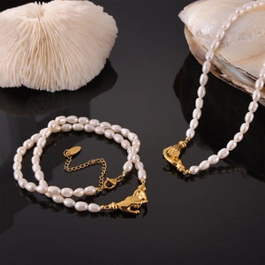 Elegant pearl necklace and bracelet set with unique golden hand-shaped clasps on black surface