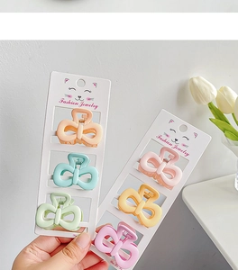 Macro view of colorful matte bow-shaped hair clips set on cute cat packaging cards