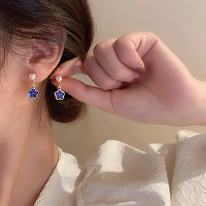 Vintage Klein blue flower earrings with white pearl and gold accents on model