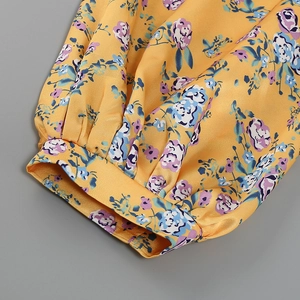 Detail of floral puff sleeve cuff with elastic gather on yellow satin fabric dress