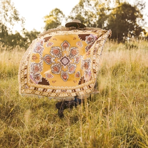 Detailed view of bohemian mandala throw blanket with tassels in a sunlit outdoor setting
