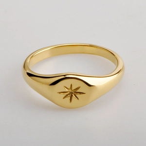 Detailed close-up of a gold-plated signet ring featuring a carved North Star motif