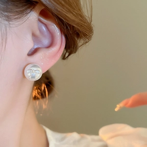 Close-up of elegant bow pearl earring with sparkling crystals on a model's ear