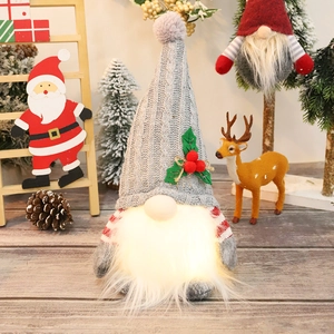 Detailed view of a glowing Christmas gnome doll with a grey knit hat on a wooden desk