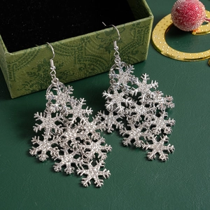 Macro shot of silver snowflake earrings with clear rhinestones on dark green texture
