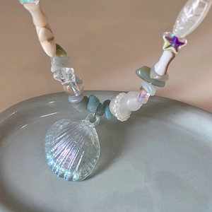 Macro shot of y2k pearl necklace with iridescent shell and star charm details