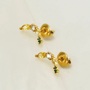 Vue macro de boucles d'oreilles banane dorées serties de zircons jaunes et verts