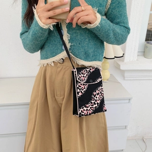 Detail of knitted mini crossbody bag featuring pink leopard print on black woven fabric