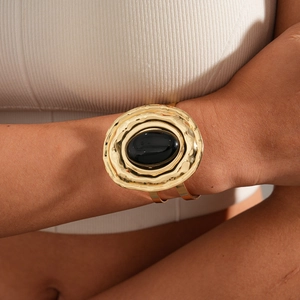Detail of chunky gold hammered cuff bracelet with oval black resin stone inlay