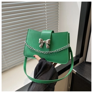 Detail of green PU leather shoulder bag with silver bow buckle and decorative chain link