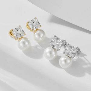 Square zircon and pearl drop earrings in gold and silver finishes on white backdrop