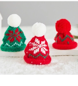 Macro view of mini knit Christmas hats with plush pom-poms on a snowy background