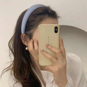 Blue padded satin headband with golden pearl earrings on a model in a mirror selfie
