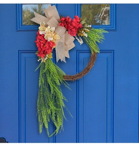 Detail of red floral wreath with burlap bow and green leaves on a blue garden door