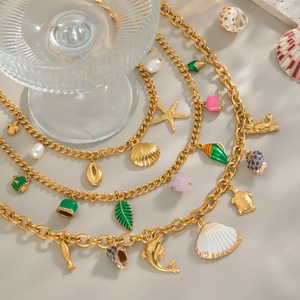 Dettaglio di collane multistrato in oro 18K con ciondoli marini e perle naturali