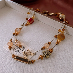 Detail shot of vintage beaded necklace with ceramic flower and amber resin pendants
