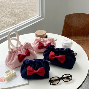 Detail of pink and navy cosmetic bags with red bows and elegant beaded edges on a white table