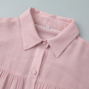 Macro detail of pink textured shirt collar with fabric-covered buttons and size label