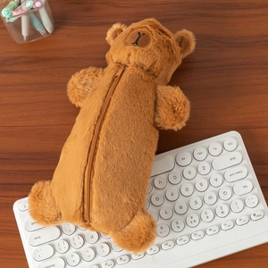 Close-up of plush capybara pencil case with brown fur and embroidery on desk