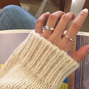 Close-up of minimalist S925 sterling silver rings worn on fingers with a knit sweater