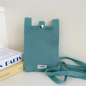 Detail of mint green knitted phone bag featuring a silver snap button closure