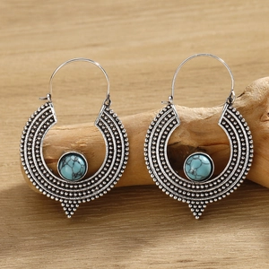 Macro view of silver Bohemian hoop earrings featuring turquoise stones on a wood surface