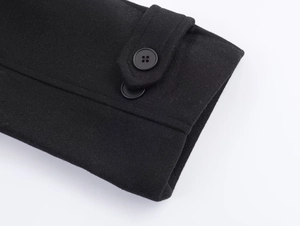 Detailed close-up of a black wool coat cuff featuring a decorative button strap design