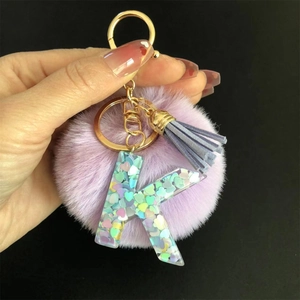 Détail du porte-clés à pompon violet avec lettre K en résine et gland bleu sur anneau
