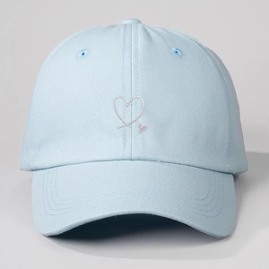Close-up of heart embroidery details and cotton fabric texture on light blue baseball cap