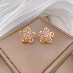 Detailed macro view of gold-plated earrings with pink gemstone flower petals