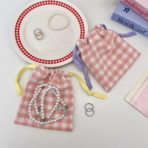 Pink checkered drawstring jewelry pouches with pearl necklaces and silver rings