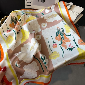 Gros plan d'un foulard en soie à fleurs avec bordure orange et texture lisse brillante