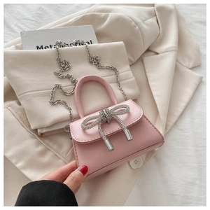 Detailed view of pink crossbody bag with sparkling rhinestone bow and silver chain strap