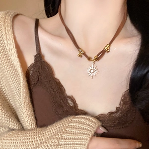 Detail of sun flower pendant on brown leather cord necklace worn by a fashion model