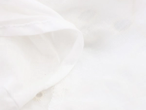 Close-up of white cotton fabric with refined embroidery details and stitching on dress
