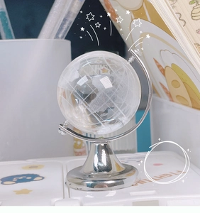 Macro shot of a mini crystal globe with silver metal base on a creative student desk