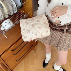 Quilted floral cosmetic bag with purple patterns and Sozakka label in a home setting