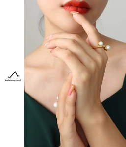 Detail of a gold stainless steel twist ring featuring two white pearls on a hand