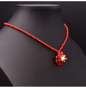 Detail einer roten Perlenkette mit weißem Perlen- und rotem Blumenanhänger am Halsmodell