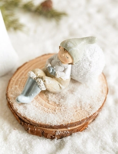 Close-up of a smiling resin angel girl figurine on a wood base with artificial snow