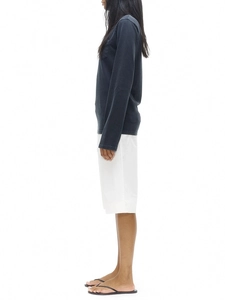 Side view of dark gray long sleeve cotton tee paired with white shorts and sandals