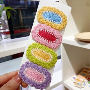 Close-up of four colorful oval knitted hair clips with detailed braided texture and stitching