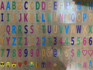 Flat lay of colorful A4 light box DIY letters, numbers, symbols, and icons on a wood background