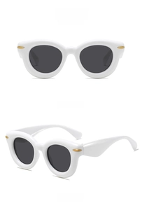 Detail view of white thick frame sunglasses with dark lenses and gold rivet accents